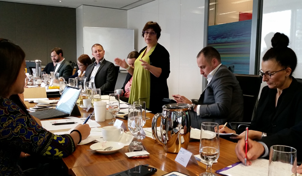 Middle aged woman with short hair leads a committee discussion in a board room